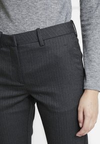 Donkergrijze pinstripe broek met een platte voorkant, slim fit en een subtiele visgraatstructuur. Bevat riemlussen en zijzakken.