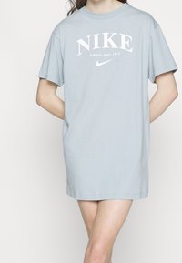 T-shirt di cotone azzurro chiaro con logo Nike bianco e testo. Maniche corte, vestibilità comoda e scollatura a girocollo.