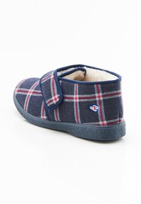 Chaussons à carreaux bleu marine avec une doublure douce, équipés d'une bride Velcro et d'une semelle en caoutchouc. Motif à carreaux rouge et blanc notable.