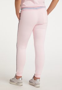 Ljusrosa leggings i stretchigt tyg med slim fit, grå randig midja och en bakficka. Bärs med silverfärgade sneakers.