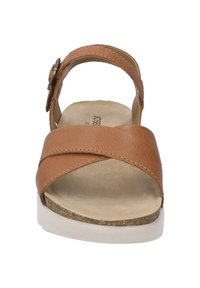 Brown leather sandal with cross strap design, adjustable buckle, and cork-textured sole. Soft inner lining and white outsole finish.