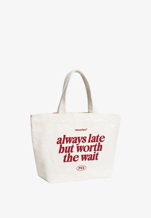 White canvas tote bag with short handles and red text reading "Neverless always late but worth the wait NVL" on the front.