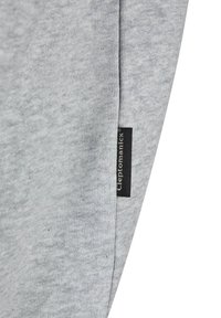 Light gray fabric with a soft texture, featuring a black label with "Cleptomanicx" on the side seam. Minimal design, no patterns.