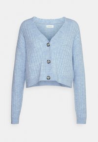 Vaaleansininen, lyhyt neulejakku, jossa on ribbineulos. Siinä on V-kaula-aukko ja kolme suurta, tummaa nappia edessä.