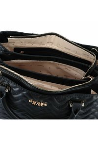 Zwarte gewatteerde handtas van leer met een goudkleurig logo, voorzien van meerdere binnencompartimenten en een gladde voering met een patroon.