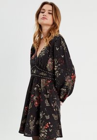 Black dress with floral and butterfly patterns in red and gold. Features a deep V-neck, puff sleeves, and a fitted waist with decorative studs.