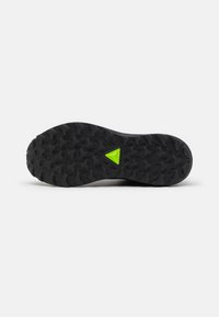 Suola di scarpa da trail running con finitura in gomma nera testurizzata, con un accentuato triangolo verde al centro per la trazione.