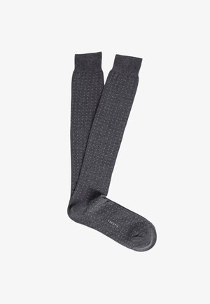 Calzini alti fino al ginocchio, di colore grigio scuro, con un motivo testurizzato di piccole palline bianche. Materiale morbido, bordo a coste, con il nome del marchio sul plantare.