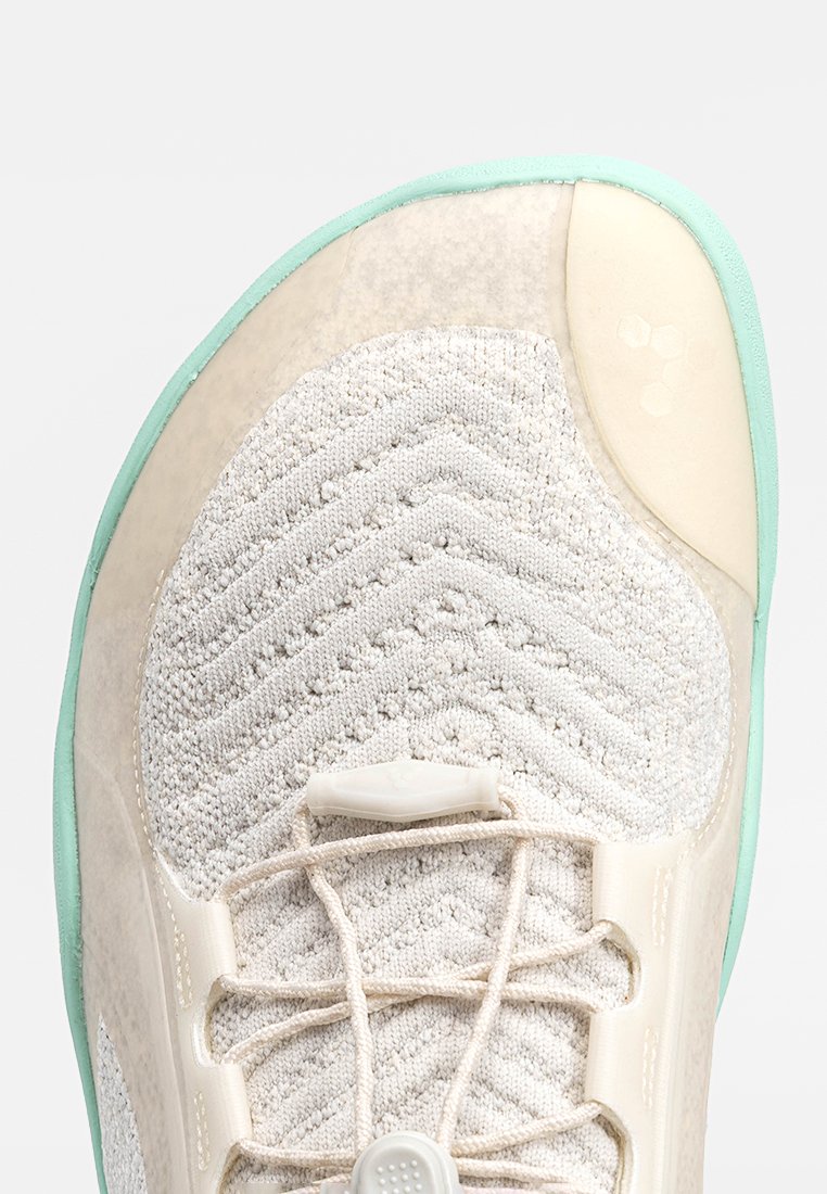 Zapatilla deportiva de color gris claro con parte superior de punto texturizado, detalles en verde menta, puntera redondeada y un sistema de cordones seguro. Suela de goma lisa.