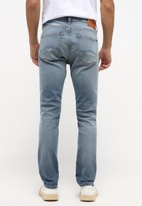 Világoskék farmernadrág, slim fit fazonnal, két hátsó zsebbel, díszvarrással és barna bőr márkajellel a derékrészen.