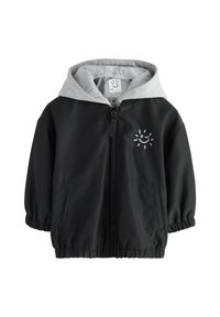 Veste légère noire avec capuche grise, poignets élastiques, fermeture éclair et poches avant. Présente un motif de soleil souriant sur la poitrine.