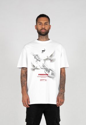 Hvid bomulds T-shirt med et grafisk design, der viser duer og kæder. Ordet "FRIHED" er trykt i rødt under designet.