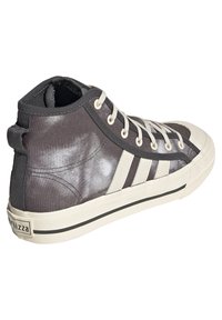 Šedé plátěné tenisky s vysokým střihem a bílou gumovou podešví. Mezi dalšími vlastnostmi jsou kontrastní bílé pruhy a texturovaný zadní panel.