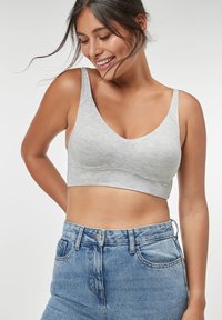 Grå bomullsblandning bralette med breda band, rundad halsringning och sömlös design. Buren med högmidjade blå jeans.