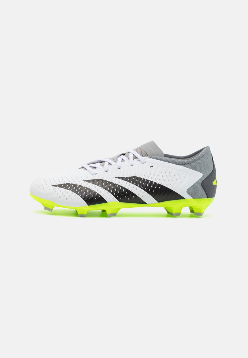 Botín de fútbol en blanco y negro con parte superior texturizada, suela amarillo-verde, talón gris y cordones blancos. Presenta un diseño ventilado y una forma deportiva.