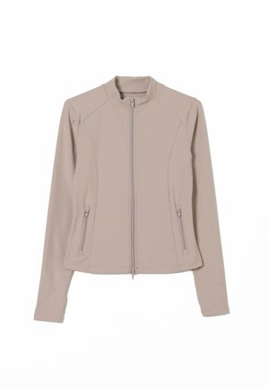 Veste zippée beige clair au design ajusté, à manches longues et avec des poches zippées sur les côtés. Tissu lisse et extensible avec un col montant.