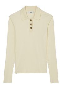 Krämfärgad långärmad polo skjorta gjord av ribbat tyg. Har en krage och tre knappar vid halsringningen. Rakt passform.