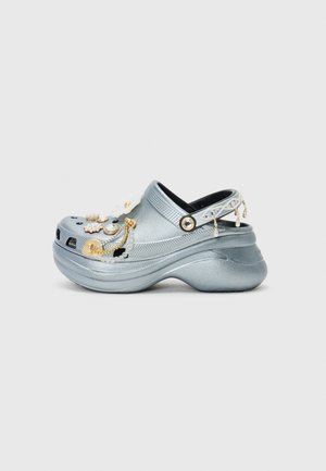 Silberne Clogs aus leichtem Material mit floralem und edelsteinverziertem Design, ausgestattet mit einer perforierten Zehenpartie und einem verstellbaren Fersenriemen.