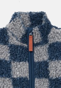 Fleece bunda s vysokým golierom, s modro-sivým kockovaným vzorom, predným zipsom s oranžovým ťahákom. Mäkká, štruktúrovaná tkanina.
