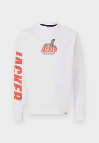 Hvid langærmet t-shirt med rød grafik, der står "JACKER" sammen med en tegneserie-squirrel. Har ribbede manchetter og et lille lilla mærke i sømmen.