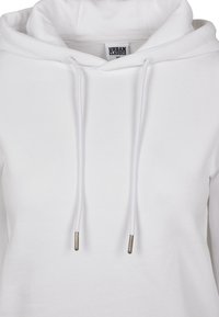 Vit hoodie gjord av mjukt tyg med snörning i huvan, silverfärgade metallspetsar och en enkel, ren design. Urban Classics-logotypen synlig.