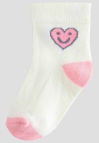Chaussette blanche avec un graphique de cœur rose comportant un visage souriant. Talon accentué en rose avec une texture côtelée sur l'ensemble.
