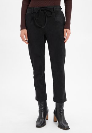 Black suede trousers with a drawstring waist, tapered fit, and smooth texture, paired with black ankle boots.