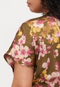 Floral blouse featuring an olive green background, pink and yellow floral pattern, short sleeves, and soft, smooth fabric texture.
