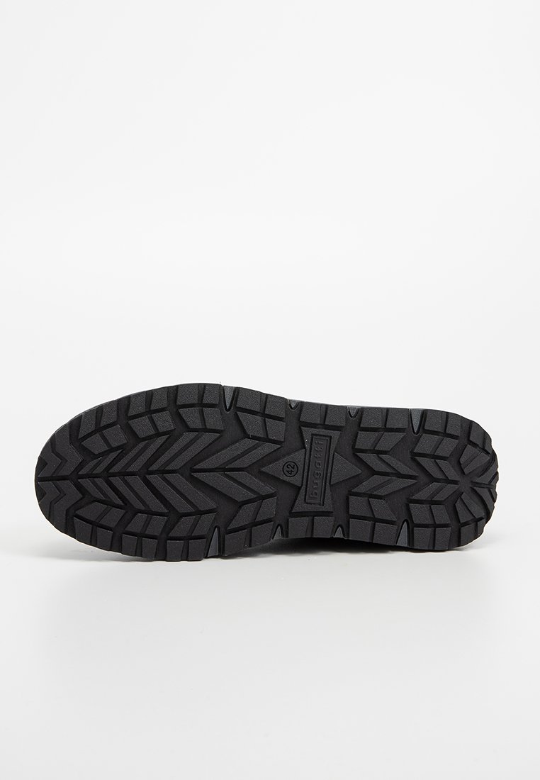 Semelle extérieure en caoutchouc noir avec un motif de bande de roulement robuste. Présente des rainures profondes et des grips angulaires pour une meilleure adhérence. Marquée avec la taille 42.