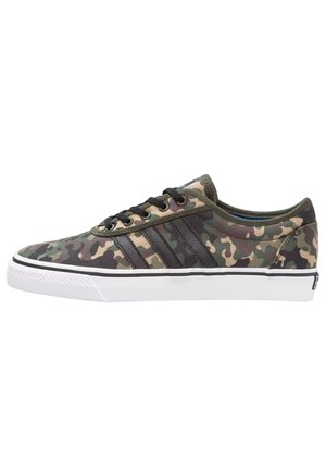 Baskets en toile camouflage avec un bout rond, des lacets noirs et trois rayures sombres contrastantes sur le côté, avec une semelle en caoutchouc blanche.