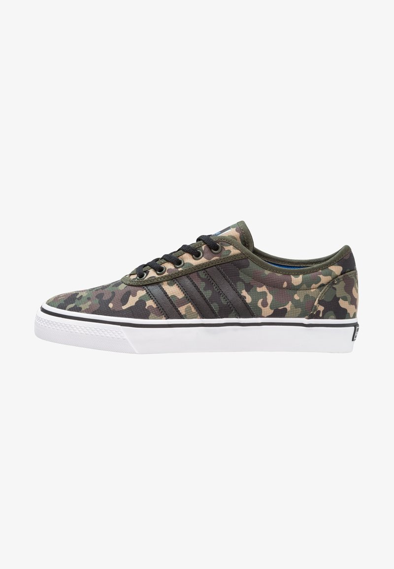 Baskets en toile camouflage avec un bout rond, des lacets noirs et trois rayures sombres contrastantes sur le côté, avec une semelle en caoutchouc blanche.