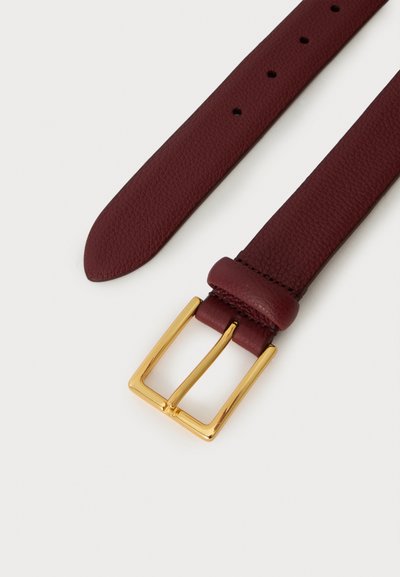 Ceinture en cuir rouge foncé avec une boucle rectangulaire dorée et plusieurs trous de réglage sur un fond clair.