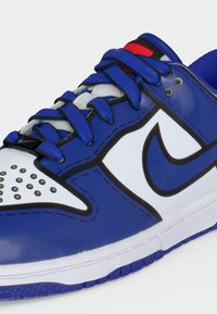 Μπλε και άσπρο αθλητικό Nike με μαύρο λογότυπο Nike swoosh, μπλε κορδόνια και άσπρο μπροστινό μέρος με μικρούς μαύρους κύκλους.