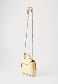 Borsa trapuntata gialla con tracolla a catena removibile, manico superiore e tasca frontale con zip. Texture liscia con finitura lucida.