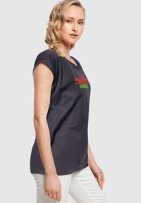 Mørk grå bomulds t-shirt med rullede ærmer, der har teksten "CHRISTMAS VIBES" i rød og grøn. Afslappet pasform og blød tekstur.