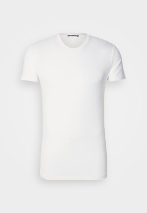 Camiseta blanca de algodón con mangas cortas, escote redondo y logo bordado en el pecho. Textura suave y diseño ajustado.