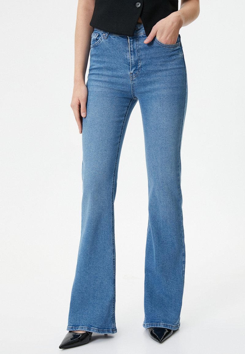 Jeans acampanados azules de tela de mezclilla, de talle alto con cinco bolsillos, con un diseño clásico y un acabado de lavado claro.