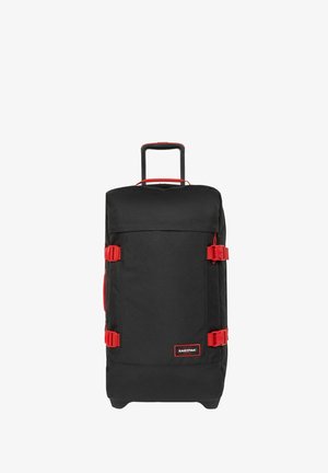 Black travel bag with red accents, durable fabric, two side handles, a retractable handle, and buckle closures. Square shape with a large main compartment.