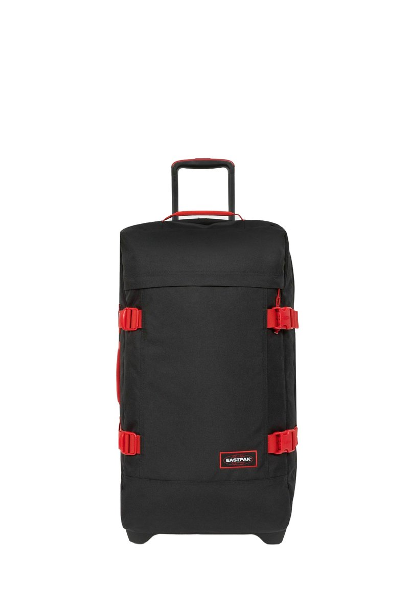 Bolsa de viaje negra con acentos rojos, fabricada en tejido duradero, con dos asas laterales, una asa retráctil y cierres de hebilla. Forma cuadrada con un gran compartimento principal.