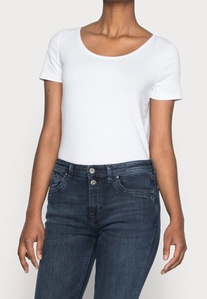 Biały t-shirt z krótkim rękawem i okrągłym dekoltem, zestawiony z ciemnoniebieskimi jeansami o klasycznym kroju z pięcioma kieszeniami i zapięciami na guziki.