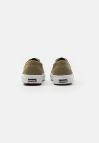 Scarpe slip-on in tela verde oliva con suola in gomma bianca, dotate di etichetta del logo sul tallone e tessuto testurizzato per una migliore aderenza.