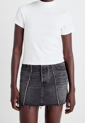 Biała koszulka z krótkim rękawem i wysokim kołnierzem, zestawiona z czarną, wysoką spódnicą jeansową z postrzępionymi krawędziami i przednimi panelami.