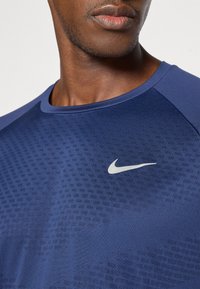 Ναυτικό μπλε αθλητικό t-shirt με κοντά μανίκια, που διαθέτει υφαντή υφή και ανακλαστικό ασημί λογότυπο Nike στο στήθος.