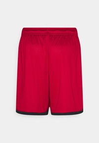 Pantalones cortos deportivos rojos con ribete negro en el dobladillo, cintura elástica y tela de malla transpirable vista desde atrás.