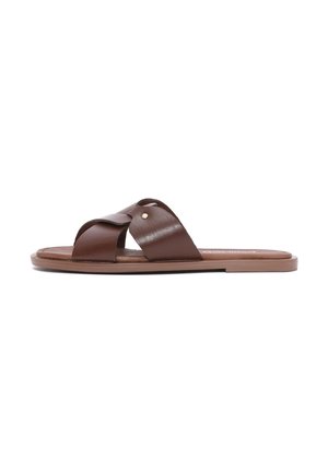 Brun flad sandal med brede korsede læderremme og en lille metalnitte på en ensartet hvid baggrund.
