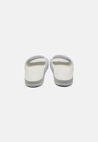 Sandali bianchi con suola interna testurizzata, suola in gomma flessibile e fascette superiori lisce, progettati per il comfort e l'uso quotidiano.