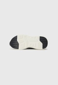 Semelle de sneaker noire avec un motif texturé blanc et des accents en caoutchouc noir ; présente des formes géométriques pour une meilleure adhérence.