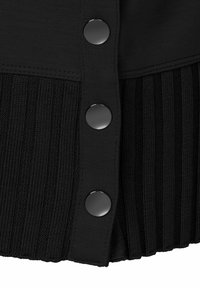 Zwarte cardigan met een geribbelde textuur aan de onderkant. Vijf glanzende zwarte knopen langs de rand voegen functionele details toe.