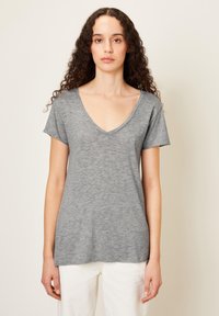 Pilkas V-kaklo marškinėliai su trumpomis rankovėmis, pagaminti iš minkštos, tekstūruotos medžiagos, pasižymintys laisvu siluetu ir tiesiu apvadu.