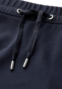Marinblå sweatpants med dragsko i midjan som har silverfärgade metalldetaljer och en texturerad tyg, vilket betonar komfort och praktisk användning.
